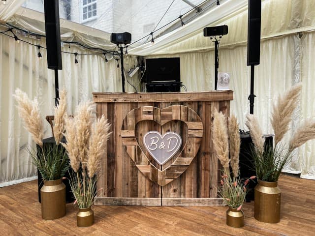 Wedding DJ performing at Tewin Bury Farm Hotel with guests dancing and vibrant lighting - Rustic Booth Setup