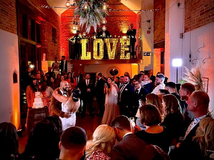 Guests dancing at a lively wedding reception with atmospheric lighting